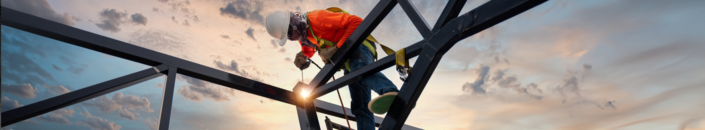 A welder is welding steel on a steel roof truss